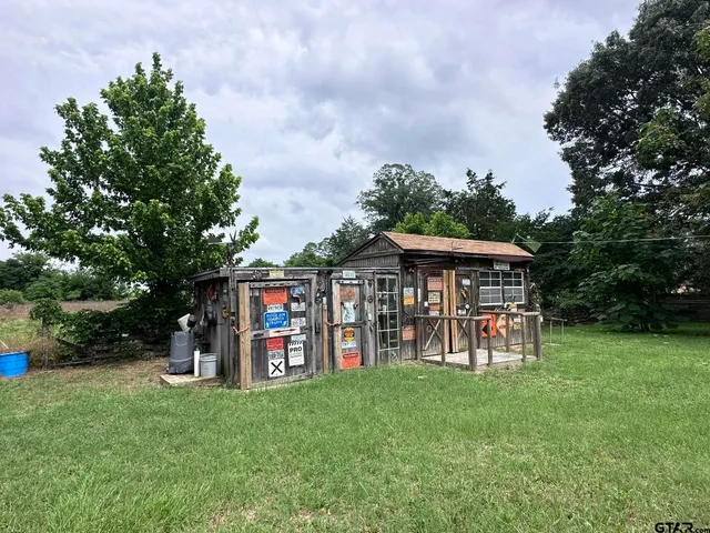 a view of a park with large trees and a wooden fence