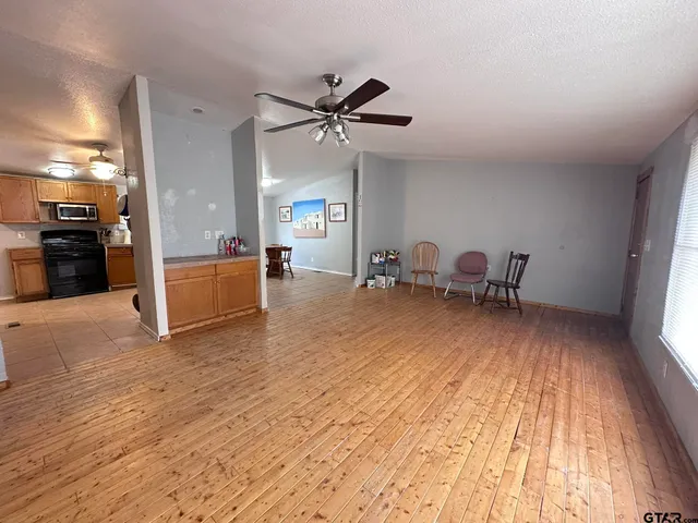 a view of a livingroom with furniture a ceiling fan and hardwood floor