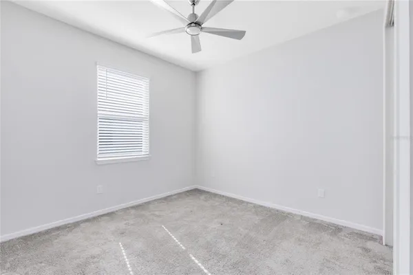an empty room with a window and a fan