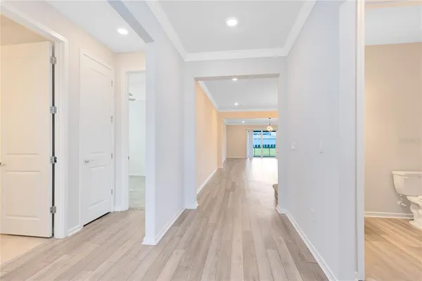 a view of a hallway with wooden floor and a bathroom