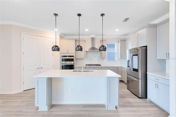 a kitchen with kitchen island a stove a refrigerator a sink and dishwasher with wooden floor