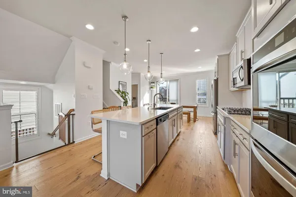 a kitchen with stainless steel appliances granite countertop a sink a stove top oven a refrigerator and a center island