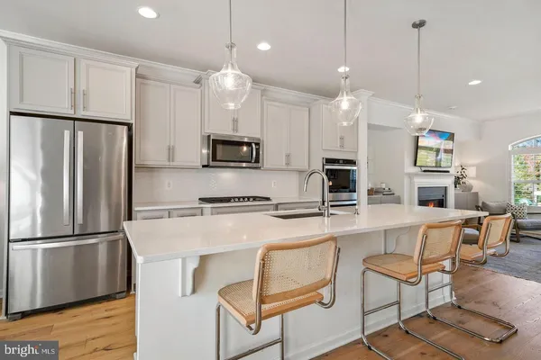 a kitchen with stainless steel appliances granite countertop a refrigerator a stove a sink a dining table and chairs with wooden floor