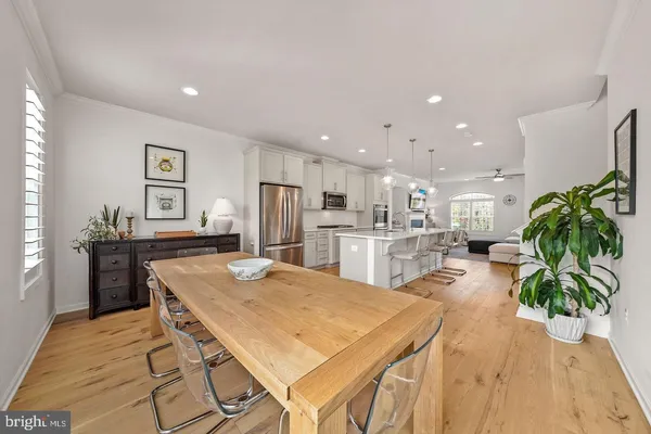 a kitchen with stainless steel appliances kitchen island granite countertop a refrigerator a stove a sink dishwasher and white cabinets with wooden floor