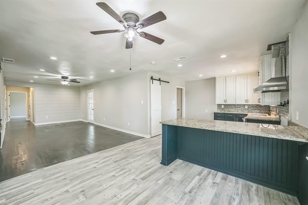 a large kitchen with stainless steel appliances a large counter top a stove and a refrigerator