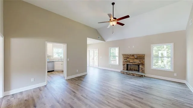 a view of a livingroom with wooden floor a ceiling fan and windows