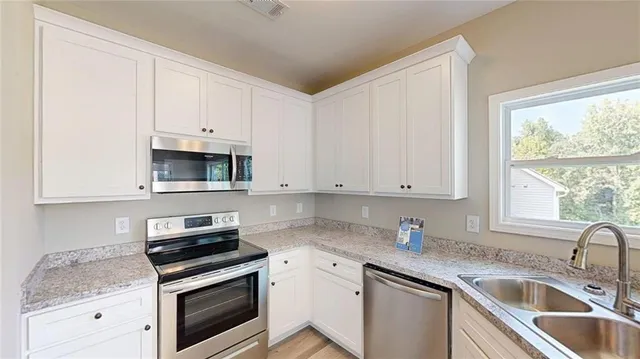 a kitchen with granite countertop white cabinets and white stainless steel appliances