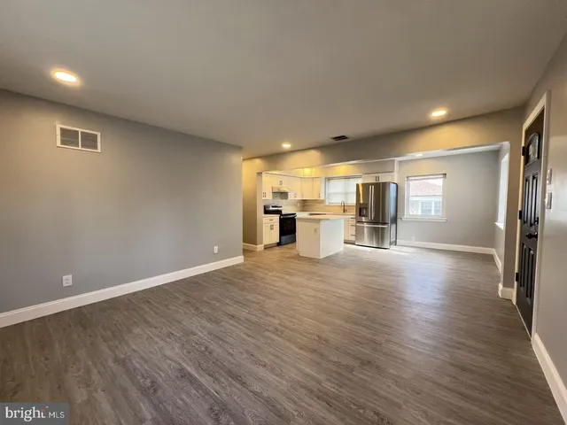 a view of a big room with wooden floor kitchen and windows