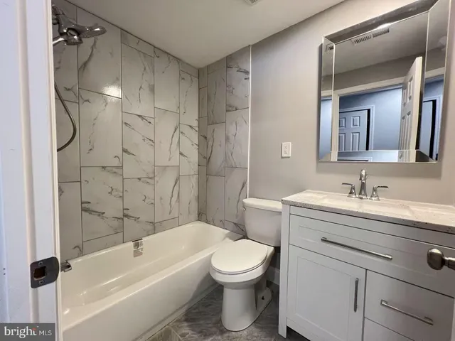 a bathroom with a granite countertop sink a toilet and a bathtub