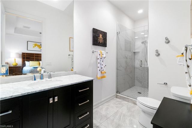 a bathroom with a granite countertop sink a toilet a mirror and shower
