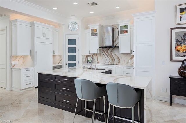 a kitchen with a sink chairs and white cabinets