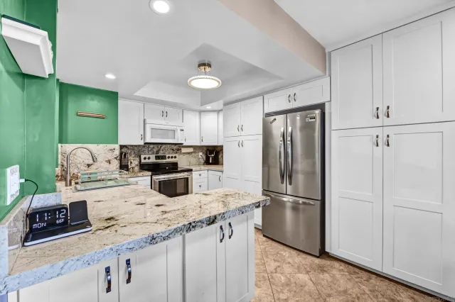 a kitchen with kitchen island granite countertop a refrigerator a sink a stove a microwave and island