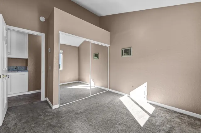 an empty room with closet and a livingroom view