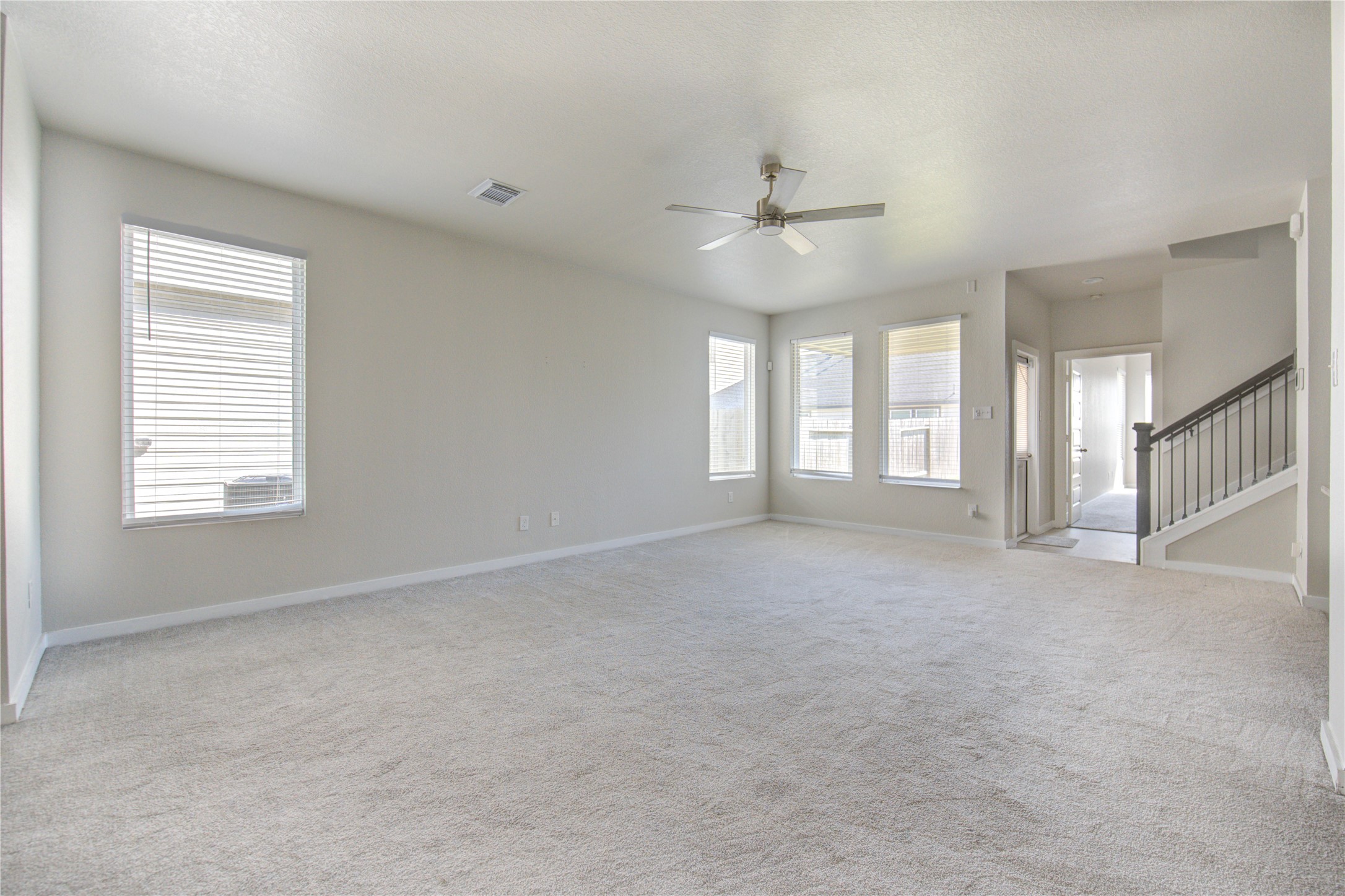 a view of an empty room with chandelier fan and fire place
