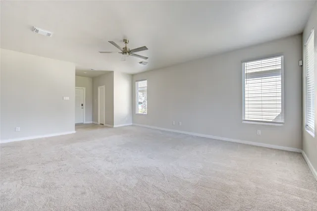 a view of an empty room with chandelier fan and fire place