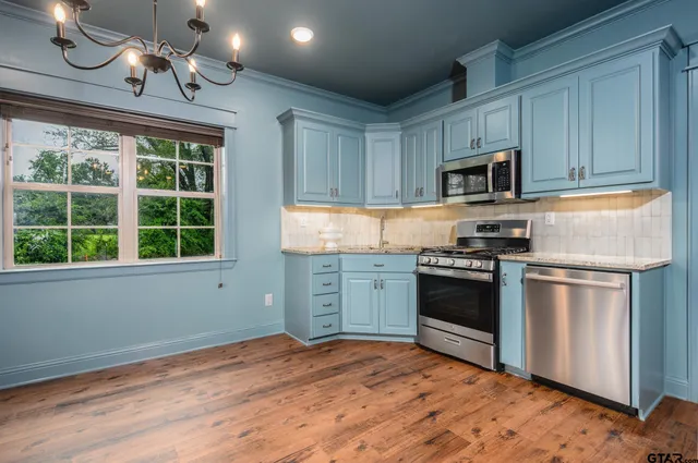 a kitchen with stainless steel appliances granite countertop a stove a sink and a microwave