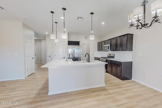a large white kitchen with living room a stove and a chandelier