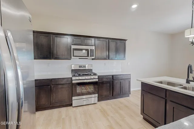 a kitchen with stainless steel appliances granite countertop a stove a sink and a microwave