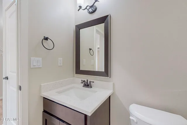 a bathroom with a toilet sink vanity and mirror
