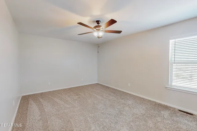 an empty room with a window and a fan