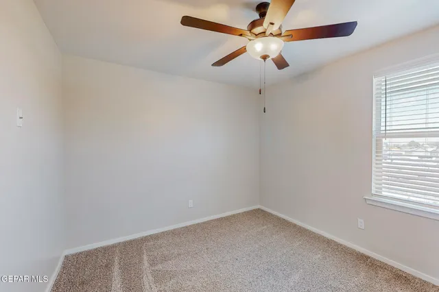 an empty room with a window and a fan