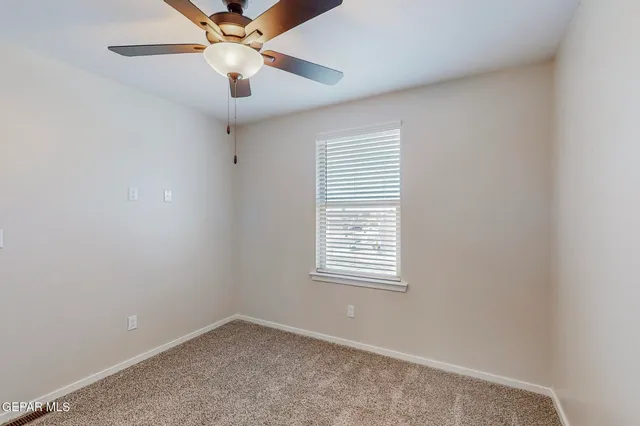 an empty room with a window and a fan