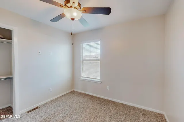 an empty room with a window and a fan
