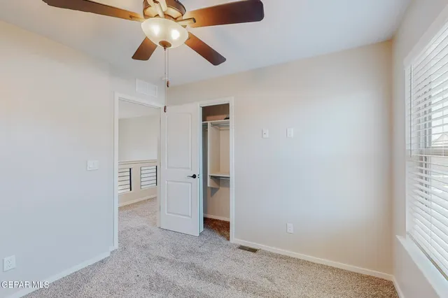 an empty room with closet and a chandelier fan
