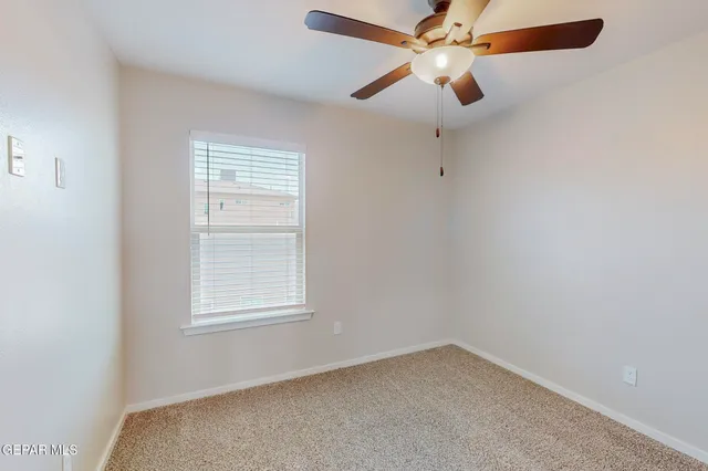 an empty room with a window and a fan