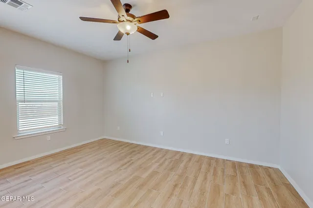 an empty room with a window and a ceiling fan