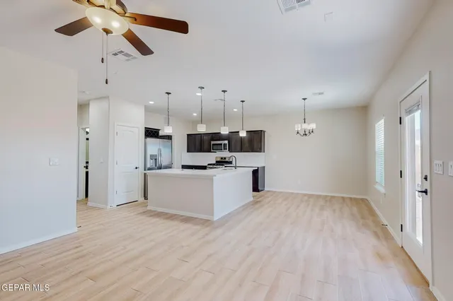a view of kitchen with stainless steel appliances kitchen island wooden floor and ceiling fan