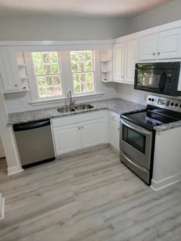 a kitchen with granite countertop wooden floors and stainless steel appliances