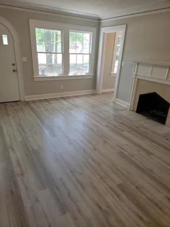 an empty room with wooden floor fireplace and windows