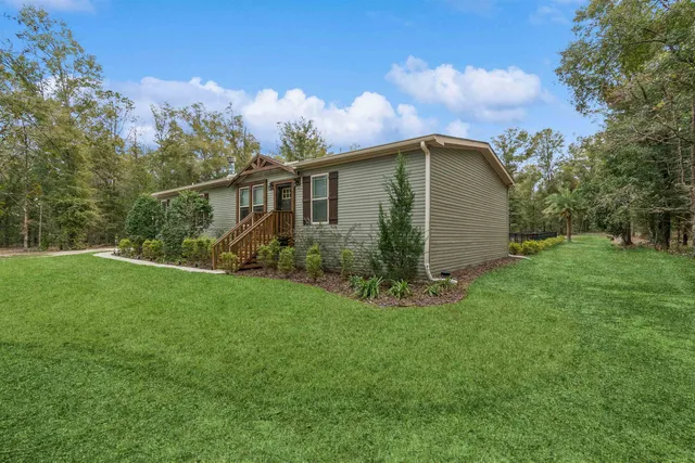 a white house with a small yard and wooden fence