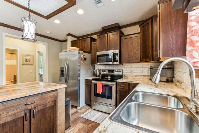 a open kitchen with stainless steel appliances granite countertop a stove a refrigerator a dining table and chairs with wooden floor