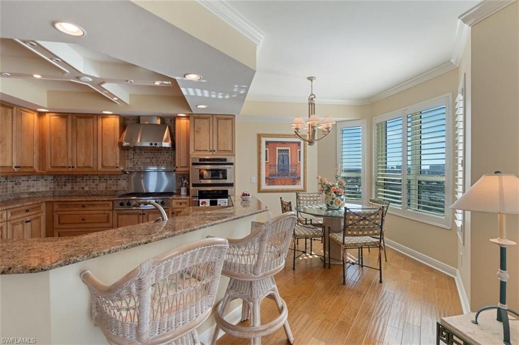 285 Grande Way, Unit 1501 Naples, FL 34110 - Photo 7 of 35 a kitchen with stainless steel appliances granite countertop a stove a sink a refrigerator dining table and chairs