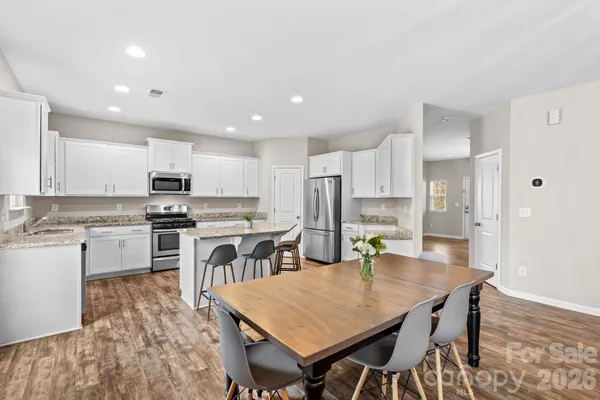 a kitchen with stainless steel appliances granite countertop a stove refrigerator a sink dishwasher with a dining table and chairs