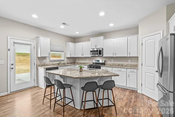 a kitchen with stainless steel appliances granite countertop a white cabinets and wooden floor