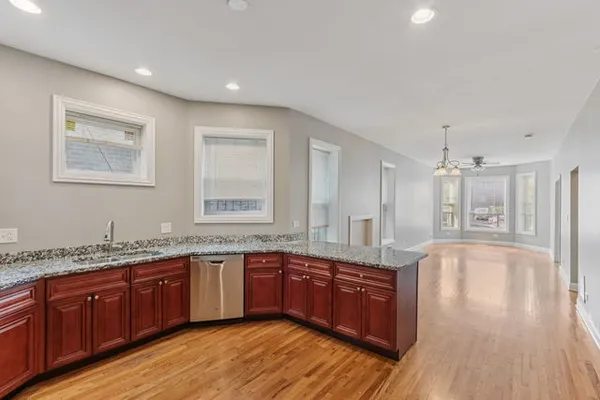 a large kitchen with granite countertop a sink counter space and wooden floor