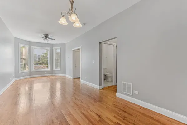 a view of an empty room with wooden floor and windows