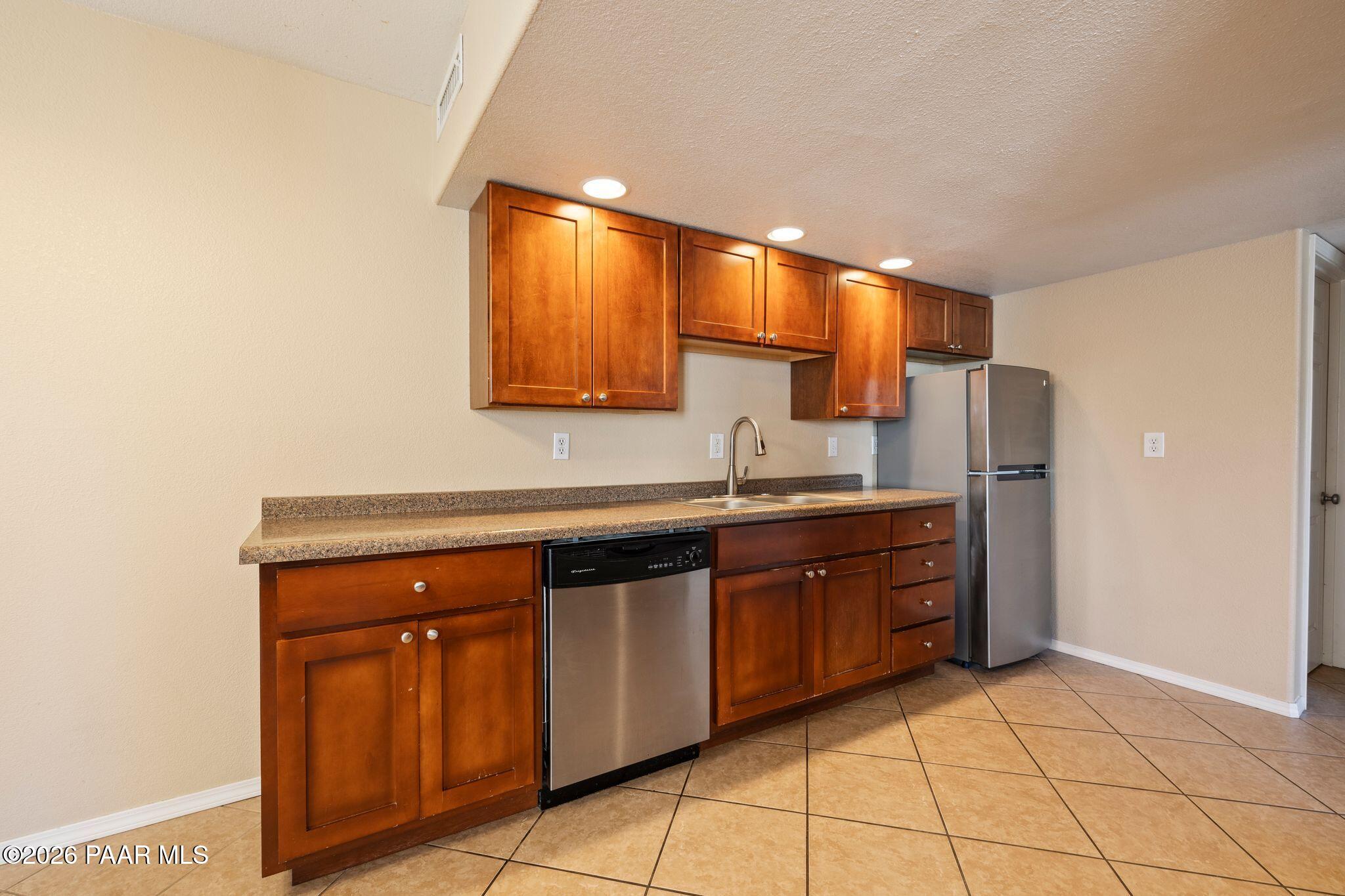 1001 East Goodwin Street, Unit 101 Prescott, AZ 86303 - Photo 5 of 23 a kitchen with stainless steel appliances granite countertop a sink and a refrigerator