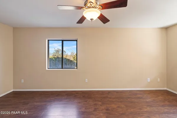 a view of an empty room with window and wooden floor