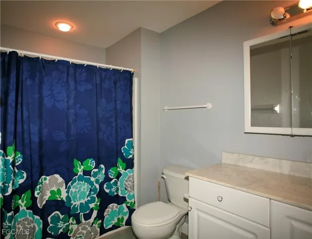a bathroom with a granite countertop sink a toilet and a window