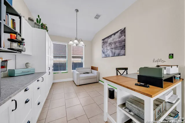 a work room with furniture a flat screen tv and a chandelier
