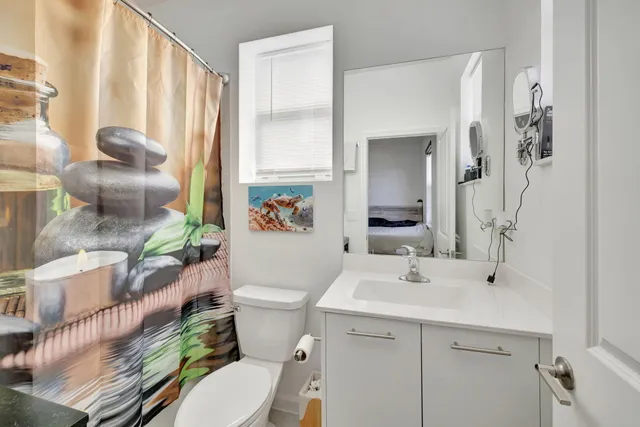 a bathroom with a sink a toilet a mirror and shower curtain