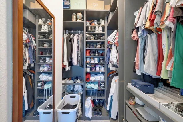 a view of walk in closet with clothes and shoes