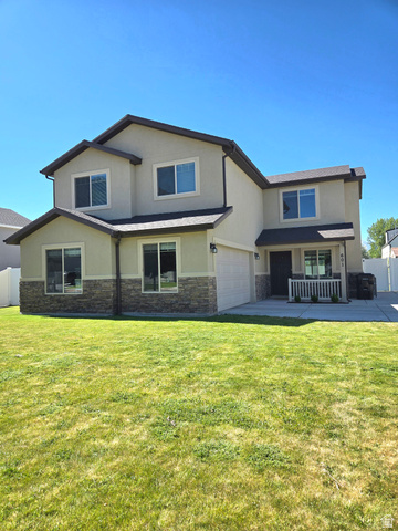 601 West 150 North, Unit 25 Springville, UT 84663 - Photo 26 of 29 Two-story stucco and stone-accented residence featuring a covered front porch, an attached garage, and a concrete driveway
