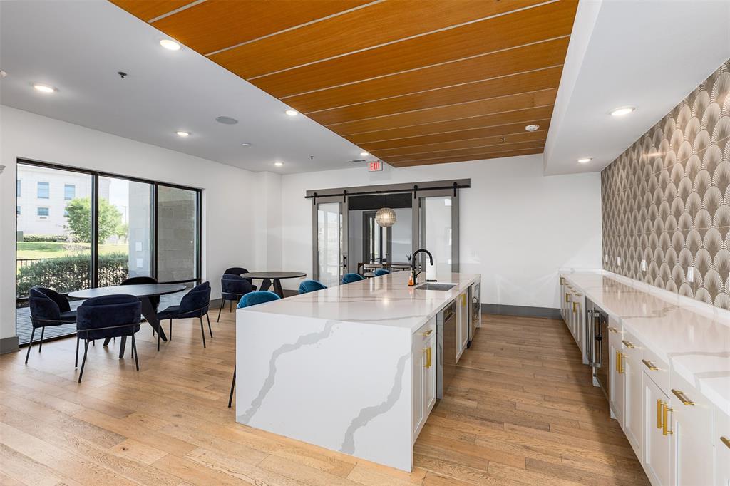 2700 Old Denton Road, Unit 1044 Carrollton, TX 75007 - Photo 24 of 33 Spacious common area featuring an expansive stone-finish island with integrated sink, wood-finish flooring, and floor-to-ceiling windows