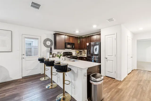 a kitchen with stainless steel appliances kitchen island a table chairs refrigerator and microwave