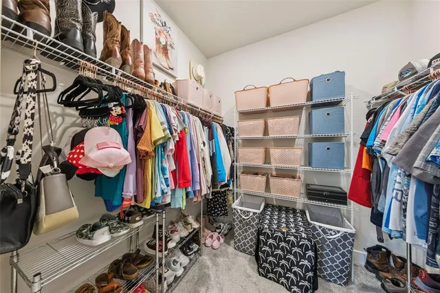 a view of walk in closet with clothes and shoes